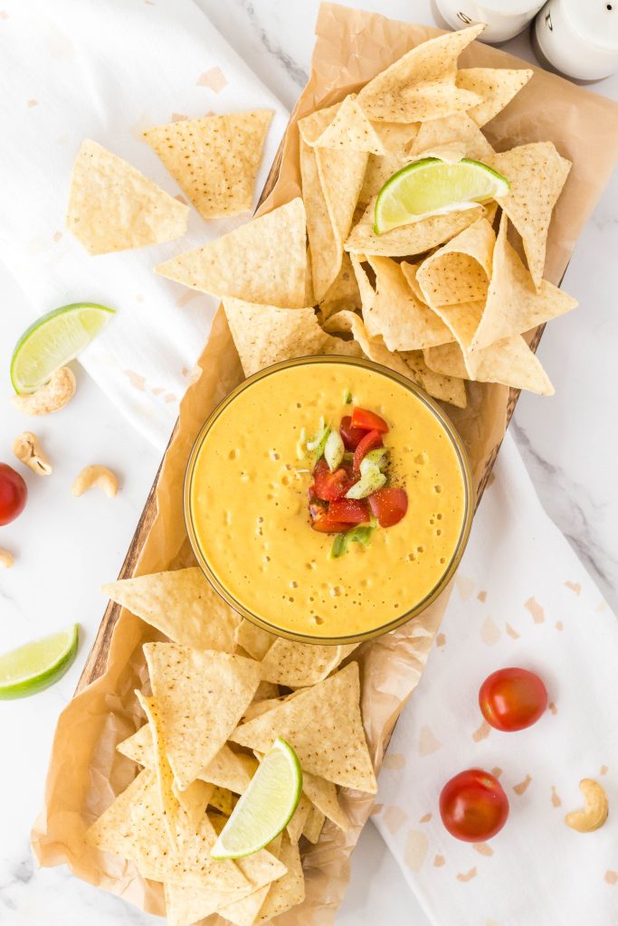 Overhead view of the vegan queso in a bowl with chips on both sides.