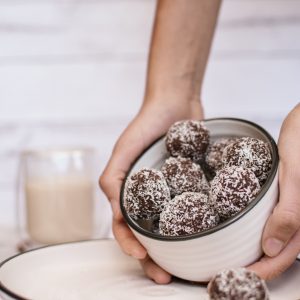 Vegan almond butter protein balls in a bowl being tilted so you can see them inside.