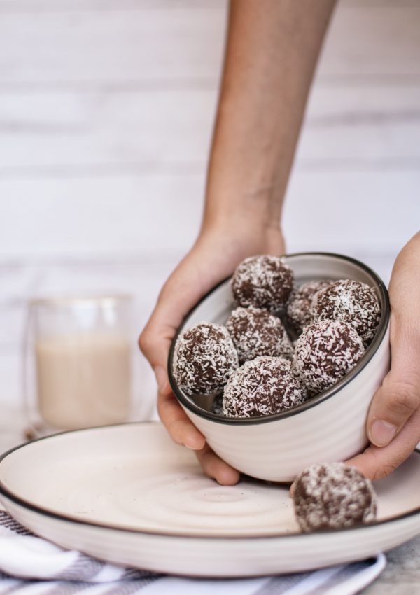 Vegan almond butter protein balls in a bowl being tilted so you can see them inside.