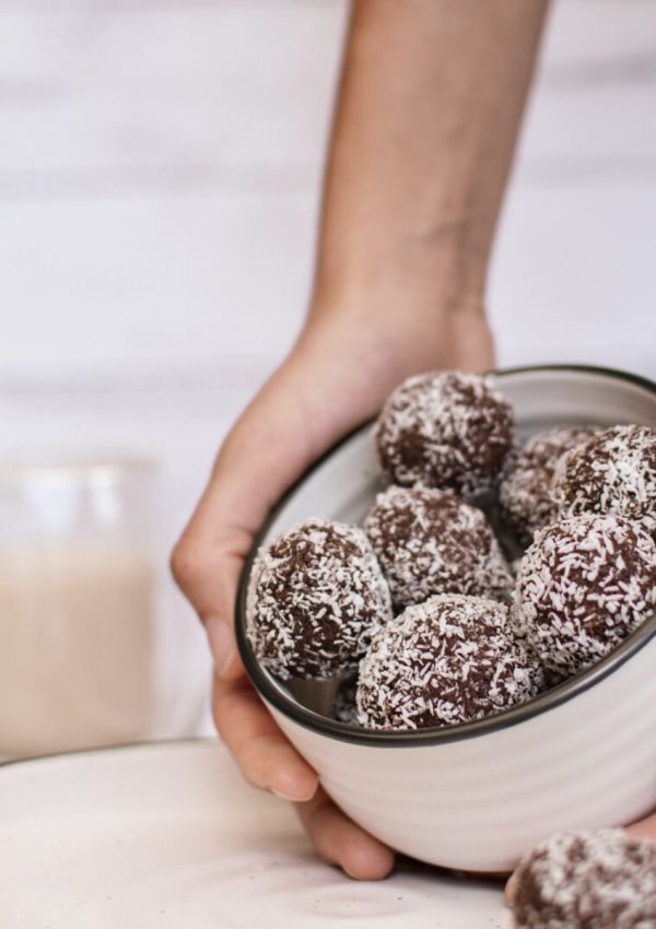 almond butter protein balls in a bowl with a cup of milk
