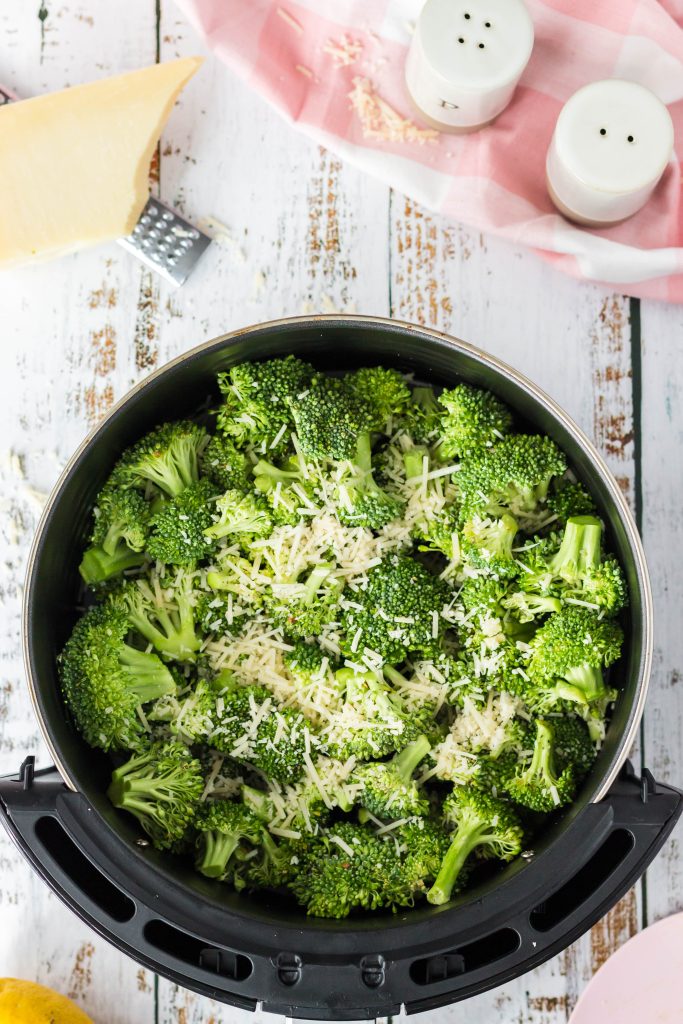 Add cut up broccoli to an air fryer basket and top with vegan parmesan.