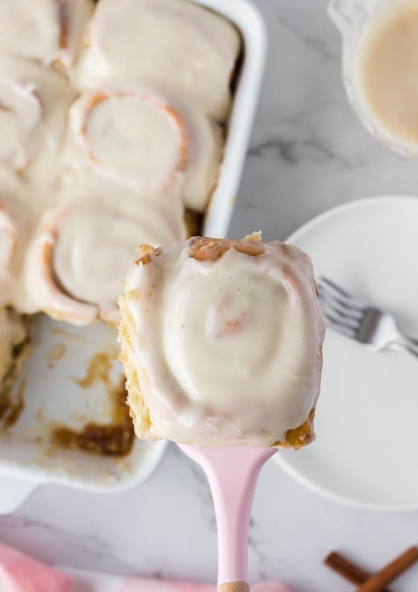 Vegan cinnamon roll in a spatula ready to be added to a plate with a fork.