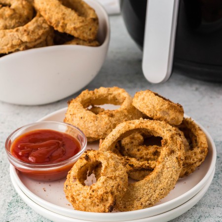 Onion rings on a plate with an air fryer in the background