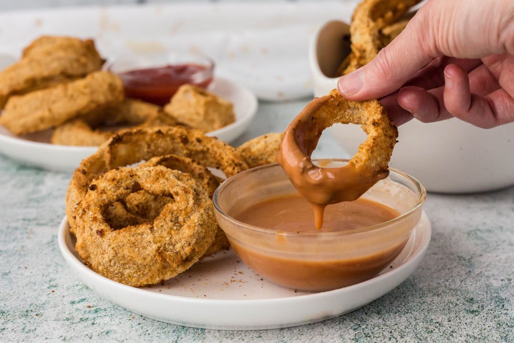 Air fryer vegan onion rings dipped in a creamy bbq sauce.