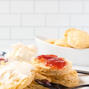 Vegan buttery biscuit on a plate with vegan butter and jam.
