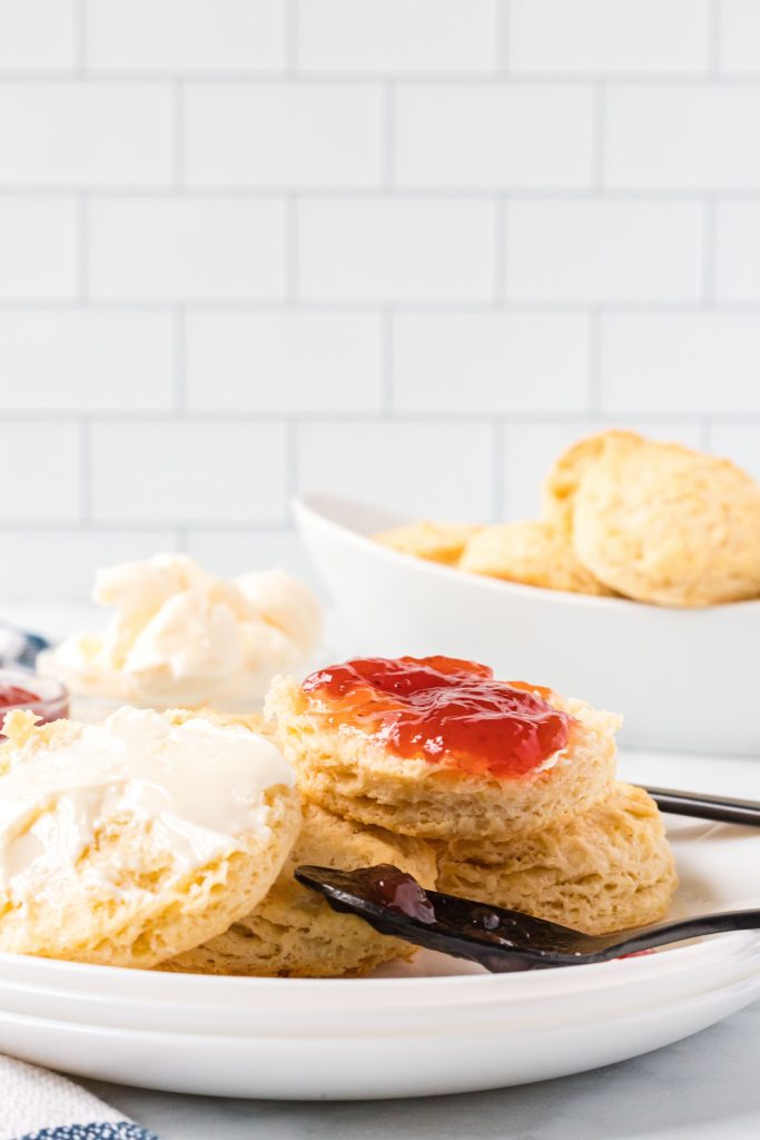 Vegan buttery biscuit on a plate with vegan butter and jam.