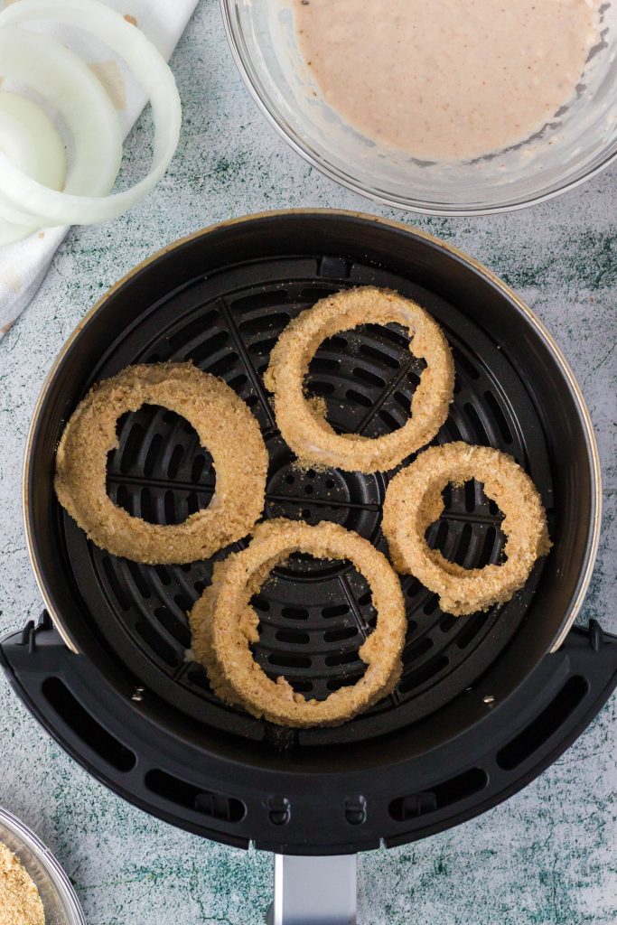 Adding already dipped onion in to air fryer basket.