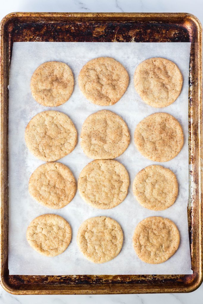 Baked vegan snickerdoodle cookies on a cookie sheet.