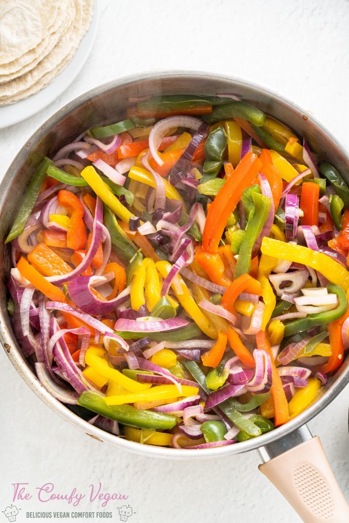 Onions and bell peppers in a saute pan.