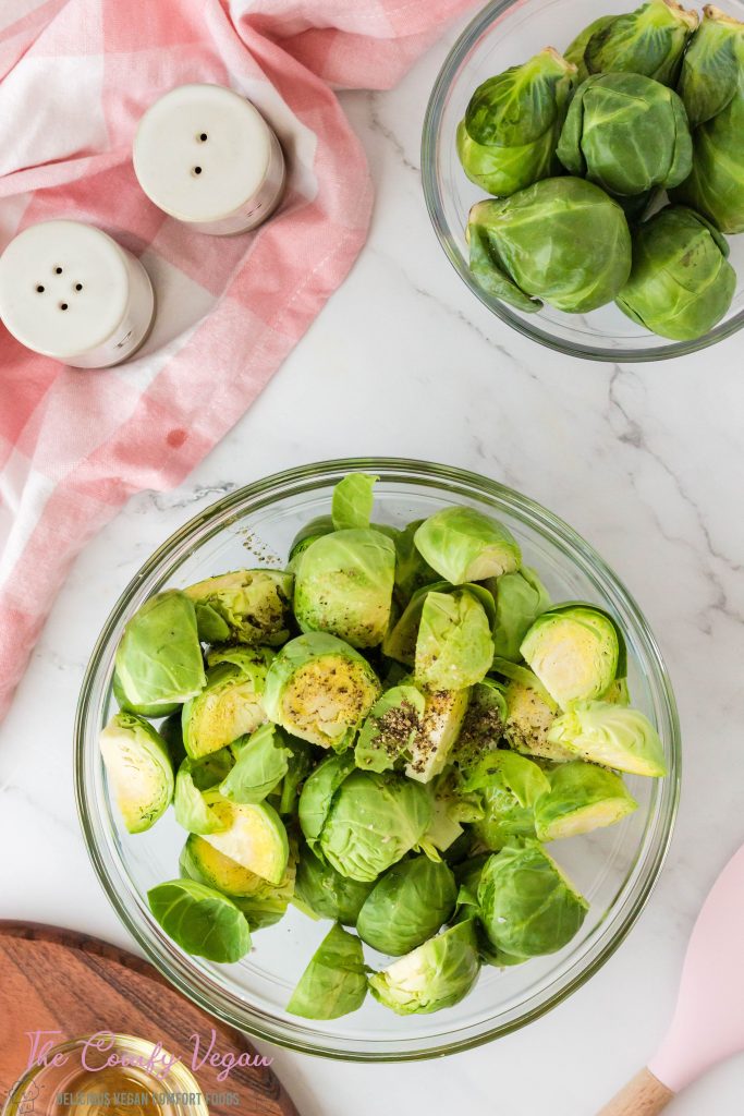 Brussels sprouts in a bowl with oil and seasonings.