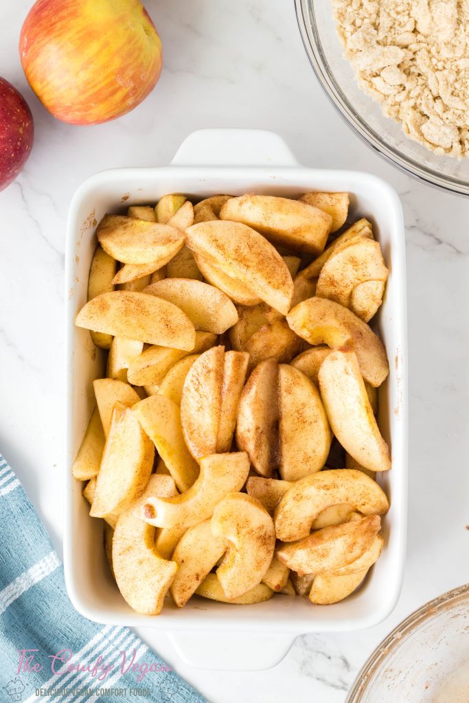 Sliced apples in a casserole dish waiting for the apple crisp topping.