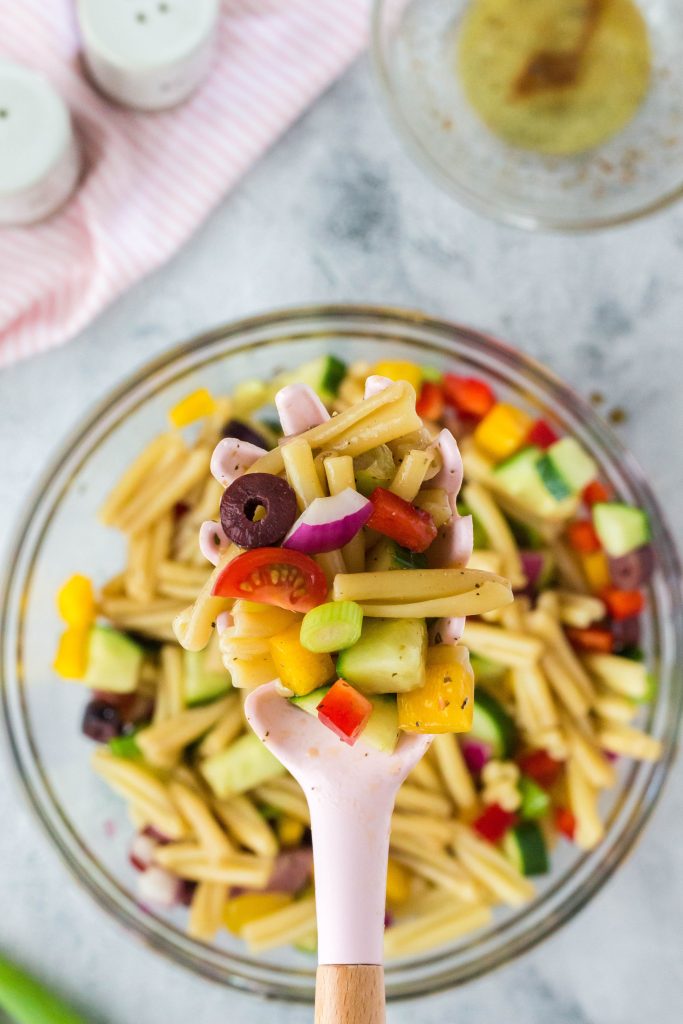 A close up view of a spoonful of vegan pasta salad.