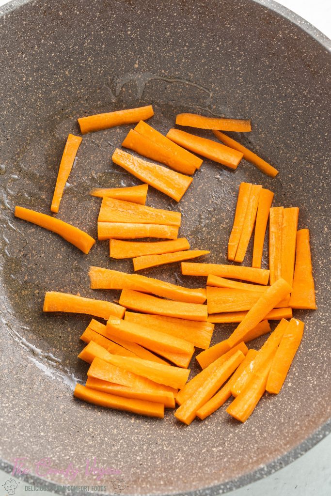 Sliced carrots in a wok with oil.