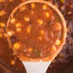 Close up overhead look at a ladle full of vegan black bean soup.