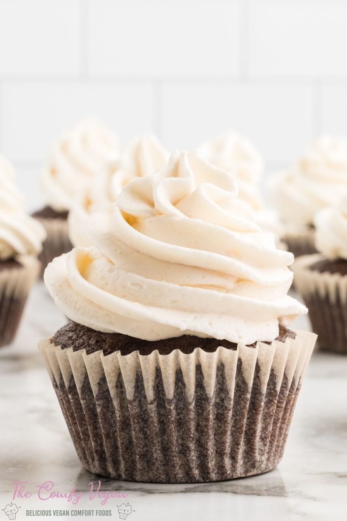 Close up of a vegan chocolate cupcake topped with vegan buttercream frosting.